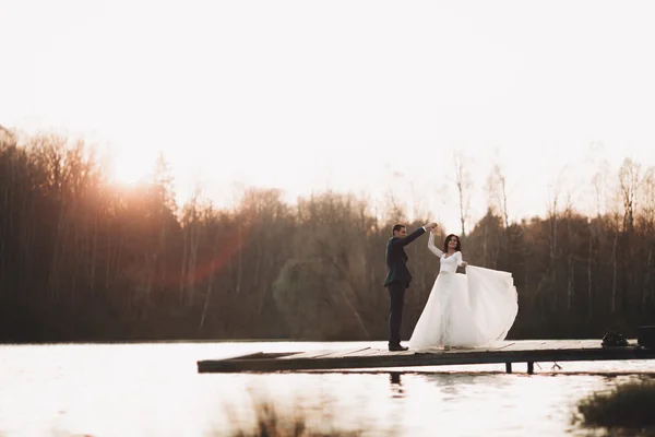 Elegante hermosa pareja de boda posando cerca de un lago al atardecer —  Fotos de Stock