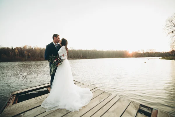 우아한 아름 다운 웨딩 커플 일몰에 호수 근처 포즈 — 스톡 사진