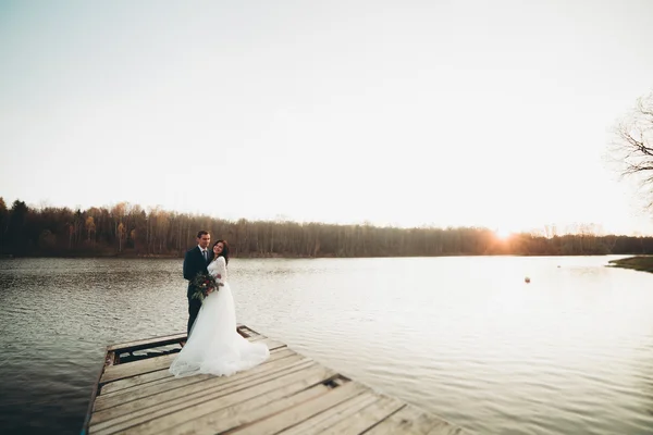 Casal lindo elegante posando perto de um lago ao pôr do sol — Fotografia de Stock