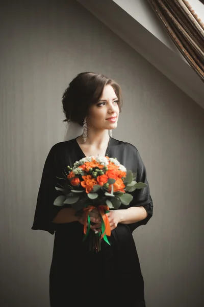 Noiva de luxo em roupão preto posando enquanto se prepara para a cerimônia de casamento — Fotografia de Stock