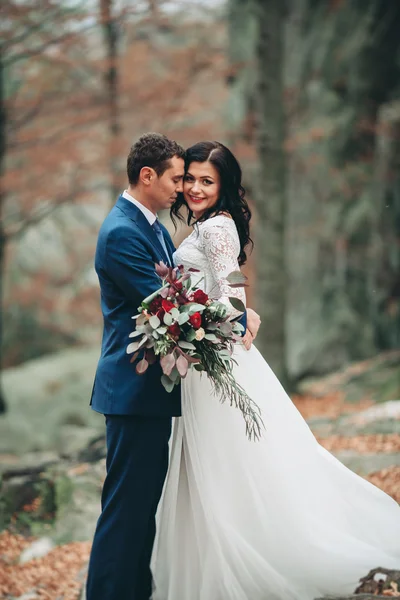 Preciosa novia, novio besándose y abrazándose cerca de los acantilados con impresionantes vistas — Foto de Stock