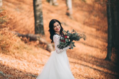 Orman ve göl poz buket tutan şık elbiseli güzel esmer gelin