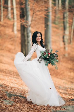 Orman ve göl poz buket tutan şık elbiseli güzel esmer gelin