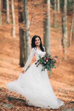 Orman ve göl poz buket tutan şık elbiseli güzel esmer gelin