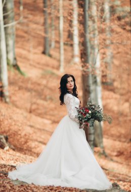 Orman ve göl poz buket tutan şık elbiseli güzel esmer gelin