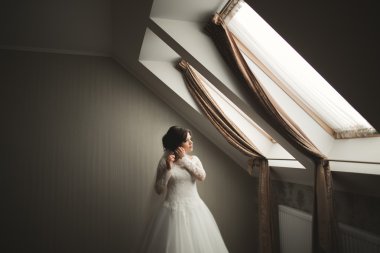 Beyaz elbiseli lüks gelin düğün törenine hazırlanırken poz veriyor.