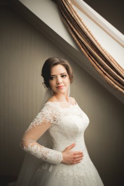 Beyaz elbiseli lüks gelin düğün törenine hazırlanırken poz veriyor.