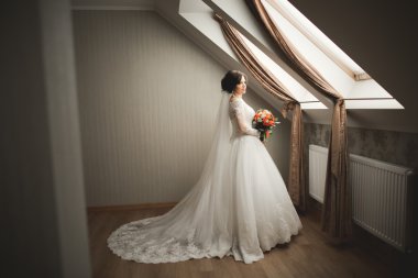 Beyaz elbiseli lüks gelin düğün törenine hazırlanırken poz veriyor.