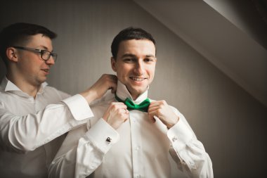 Mutlu arkadaş yardımcı olur şık damat onun düğün günü için hazırlanıyor