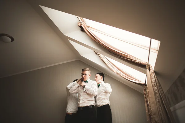 Happy vänner hjälper eleganta brudgummen sig redo för sin bröllopsdag — Stockfoto