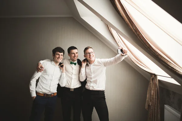 Щасливі друзі допомагають стильному нареченому готуватися до свого весілля — стокове фото