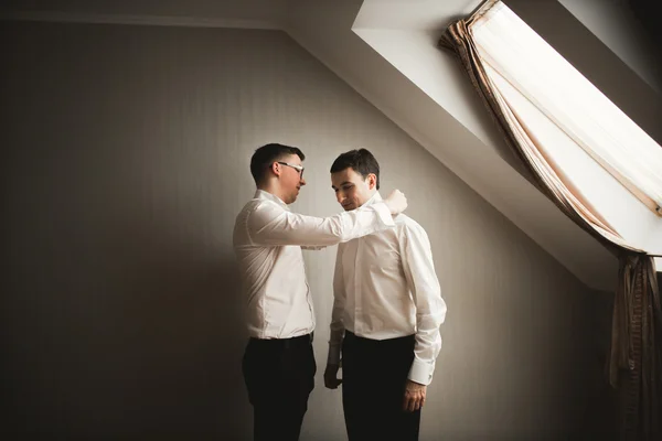 Amigos felizes ajuda o noivo elegante se preparando para seu dia do casamento — Fotografia de Stock