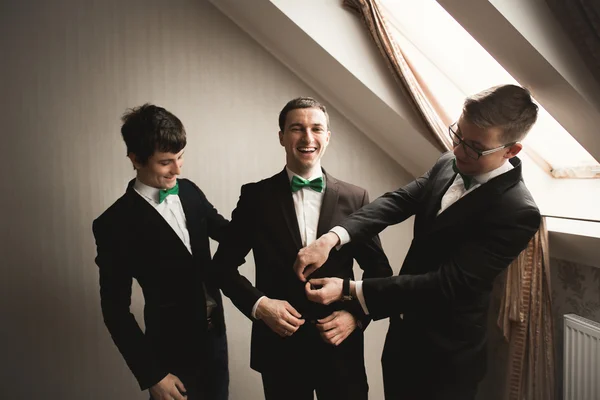 Szczęśliwy, przyjaciele pomaga stylowe pana młodego, szykując się do jego ślubu — Zdjęcie stockowe