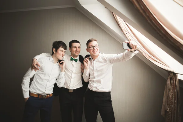 Amigos felizes ajuda o noivo elegante se preparando para seu dia do casamento — Fotografia de Stock