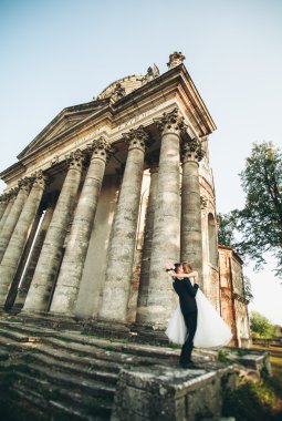 Güzel, romantik bir düğün. Yeni evliler. Eski kalenin yakınlarında sarılıyorlar.