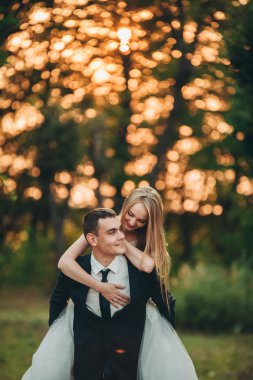 Güzel romantik bir çift yeni evliler gün batımında parkta sarılıyorlar.