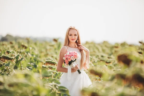 長い髪とフィールドのヒマワリの花束とエレガントな金髪の花嫁 — ストック写真