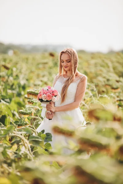 Elegant blonde bride with long hair and a bouquet of sunflowers in the field — Stock Photo, Image