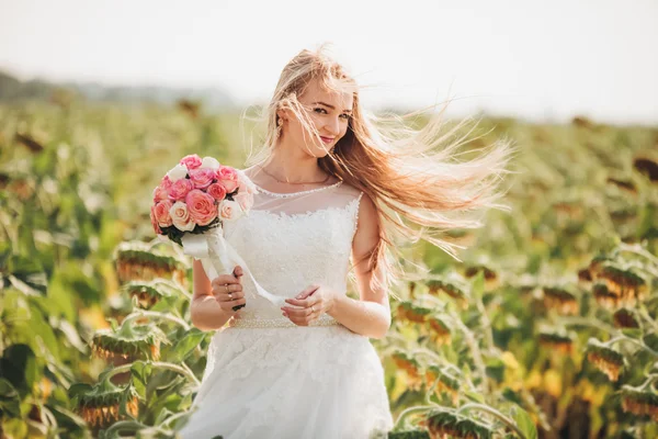 Noiva loira elegante com cabelos longos e um buquê de girassóis no campo — Fotografia de Stock