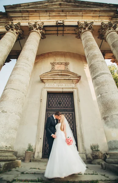 Güzel, romantik bir düğün. Yeni evliler. Eski kalenin yakınlarında sarılıyorlar.