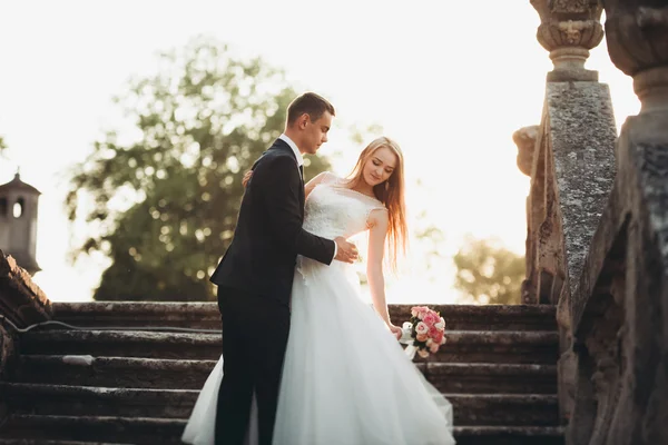 Beau couple de mariage romantique de jeunes mariés étreignant près du vieux château au coucher du soleil — Photo