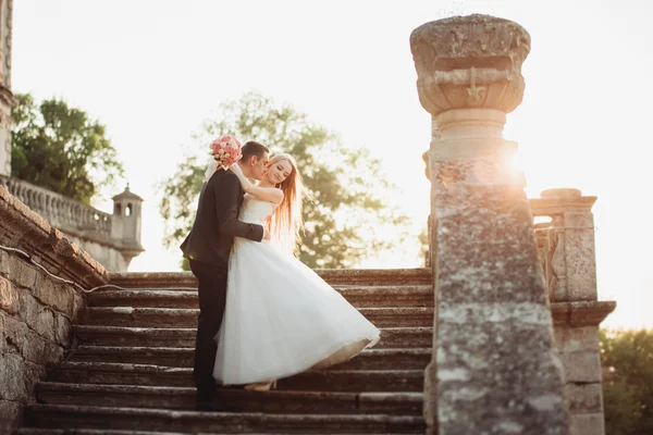 Bella coppia di sposi romantici che si abbracciano vicino al vecchio castello al tramonto — Foto Stock