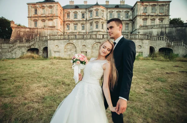 Bella coppia di matrimoni romantici, sposo e sposa che si abbracciano vicino al vecchio castello al tramonto — Foto Stock