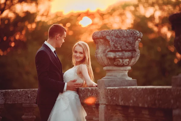 Όμορφο ρομαντικό γάμο ζευγάρι, γαμπρός και νύφη αγκάλιασμα κοντά στο παλιό κάστρο στο ηλιοβασίλεμα — Φωτογραφία Αρχείου