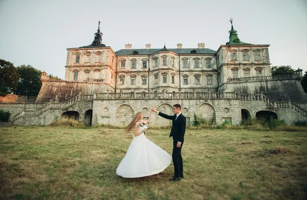 Красивая романтическая свадебная пара, жених и невеста обнимаются возле старого замка на закате — стоковое фото