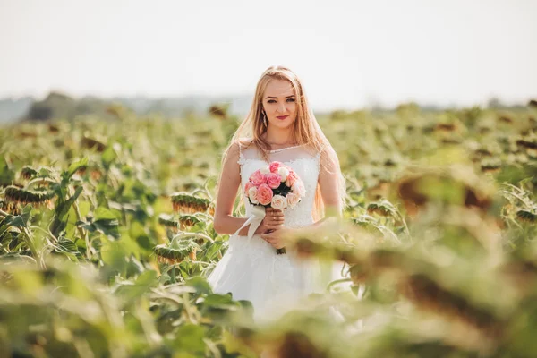 Noiva loira elegante com cabelos longos e um buquê de girassóis no campo — Fotografia de Stock