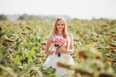 Uzun saç ve ayçiçeği alanında bir buket ile zarif sarı gelin