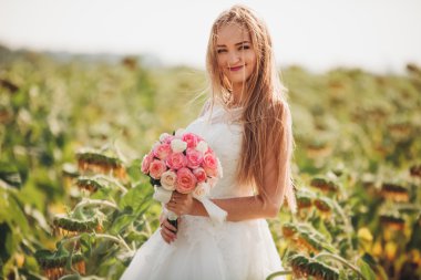 Uzun saç ve ayçiçeği alanında bir buket ile zarif sarı gelin