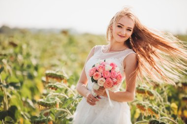 Uzun saç ve ayçiçeği alanında bir buket ile zarif sarı gelin