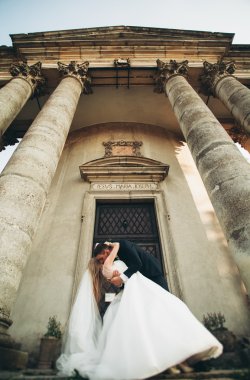 Güzel, romantik bir düğün. Yeni evliler. Eski kalenin yakınlarında sarılıyorlar.