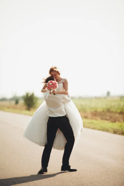 Hermosa pareja de boda, novia y novio posando en el camino —  Fotos de Stock