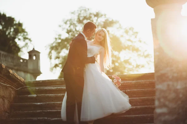 Beau couple de mariage romantique de jeunes mariés étreignant près du vieux château au coucher du soleil — Photo