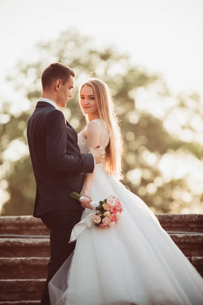 Beau couple de mariage romantique de jeunes mariés étreignant près du vieux château au coucher du soleil — Photo