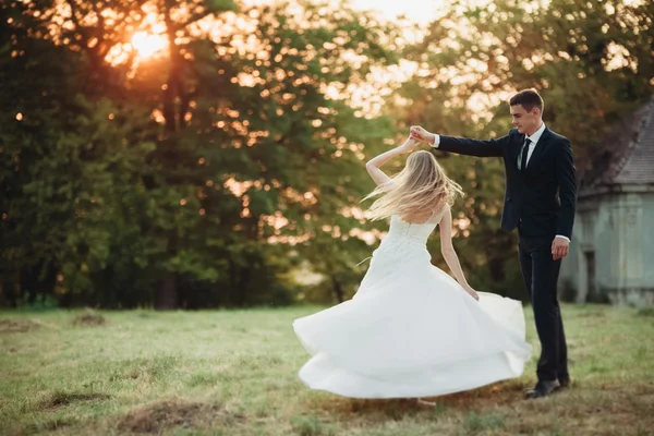 Hermosa pareja romántica de boda, novio y novia abrazándose cerca del viejo castillo en la puesta del sol —  Fotos de Stock