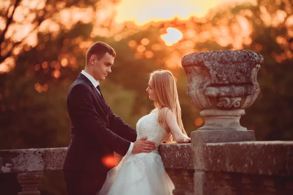 Krásné romantické svatební pár, ženich a nevěsta objímání poblíž starého hradu na západ slunce — Stock fotografie