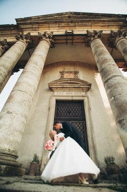 Güzel, romantik bir düğün. Yeni evliler. Eski kalenin yakınlarında sarılıyorlar.