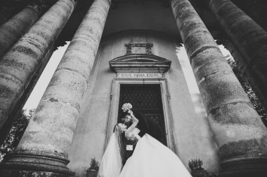 Güzel, romantik bir düğün. Yeni evliler. Eski kalenin yakınlarında sarılıyorlar.