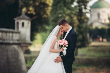 Güzel, romantik bir düğün. Yeni evliler. Eski kalenin yakınlarında sarılıyorlar.