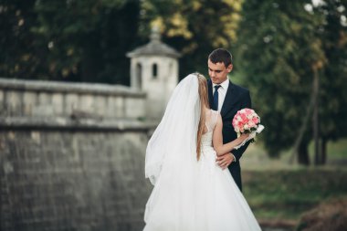 Güzel, romantik bir düğün. Yeni evliler. Eski kalenin yakınlarında sarılıyorlar.