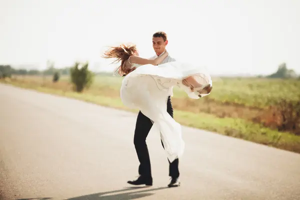 Hermosa pareja de boda, novia y novio posando en el camino — Foto de Stock