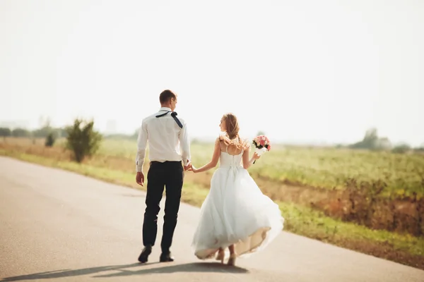 Beautiful wedding couple, bride and groom posing on road — Stock Photo, Image