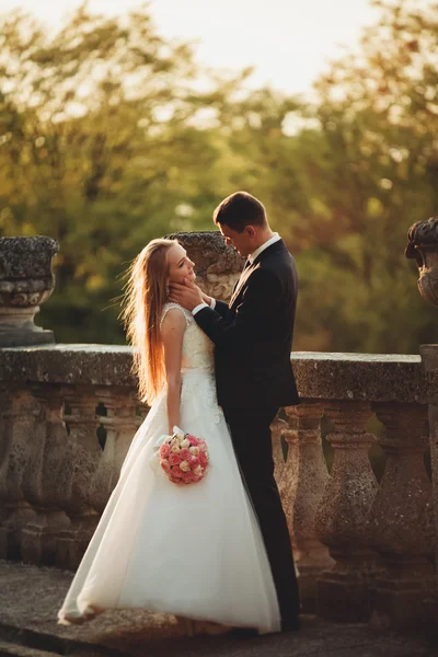 Vackra romantiska bröllop par nygifta kramas nära gamla slottet på sunset — Stockfoto