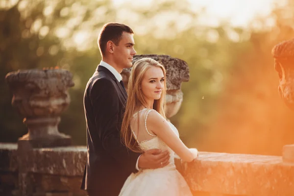 Casal romântico bonito casal de recém-casados abraçando perto do castelo velho no pôr do sol — Fotografia de Stock