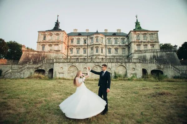 美丽的浪漫婚礼情侣，新郎和新娘日落在旧城堡附近拥抱 — 图库照片
