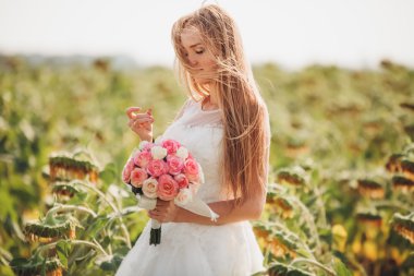 Uzun saç ve ayçiçeği alanında bir buket ile zarif sarı gelin