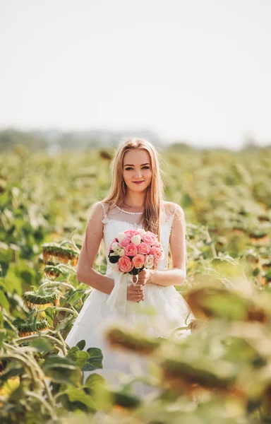 Elegant blonde bride with long hair and a bouquet of sunflowers in the field — Stock Photo, Image